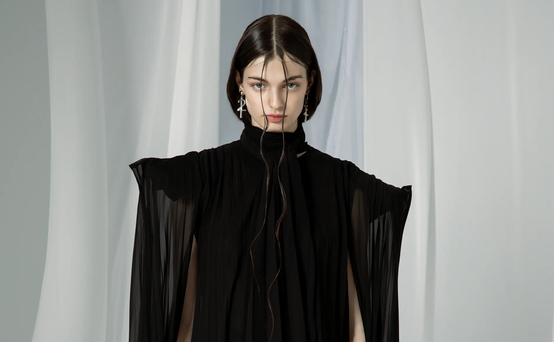 Model in a sheer black high-neck tunic with split, cape-like sleeves