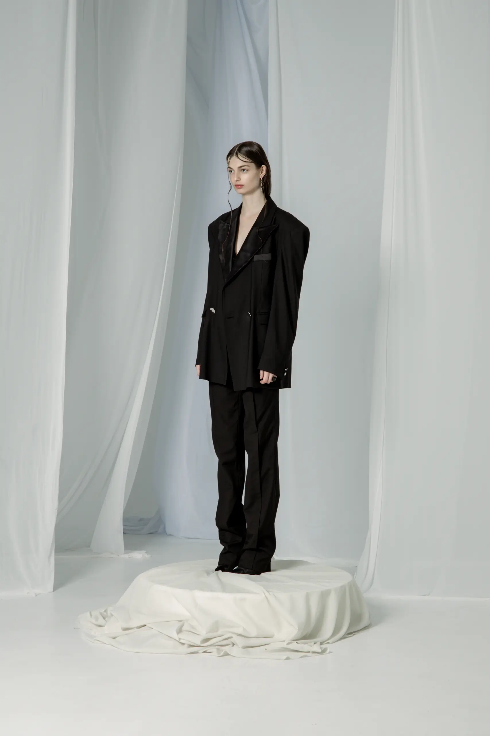 Crno oversize smoking odelo sa satenskim reverima, model u poluprofilu